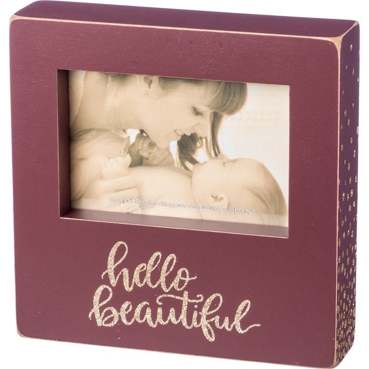 Wooden box picture frame that holds a portrait style photo. Box frame is maroon with Hello Beautiful wrote in gold glitter. 